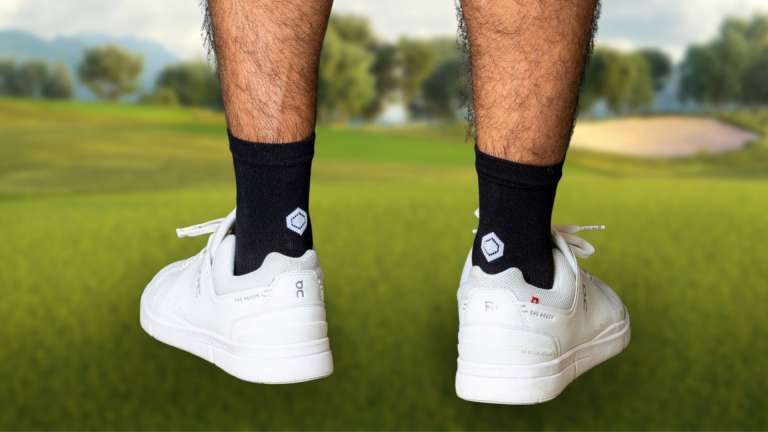 Beine eines Golfers mit Socken und Schuhen auf dem Grün