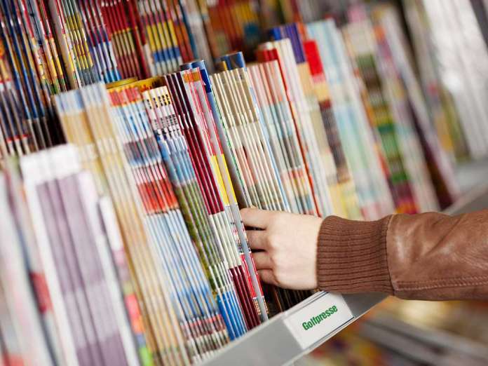 Eine Hand greift nach einer Golfzeitschrift aus einem Stapel von Golfzeitungen